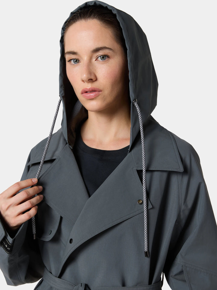 The ThermaShape Belted Coat in Outer Space Green worn with the hood up and the belt tied, a hand at the drawcord, head to waist