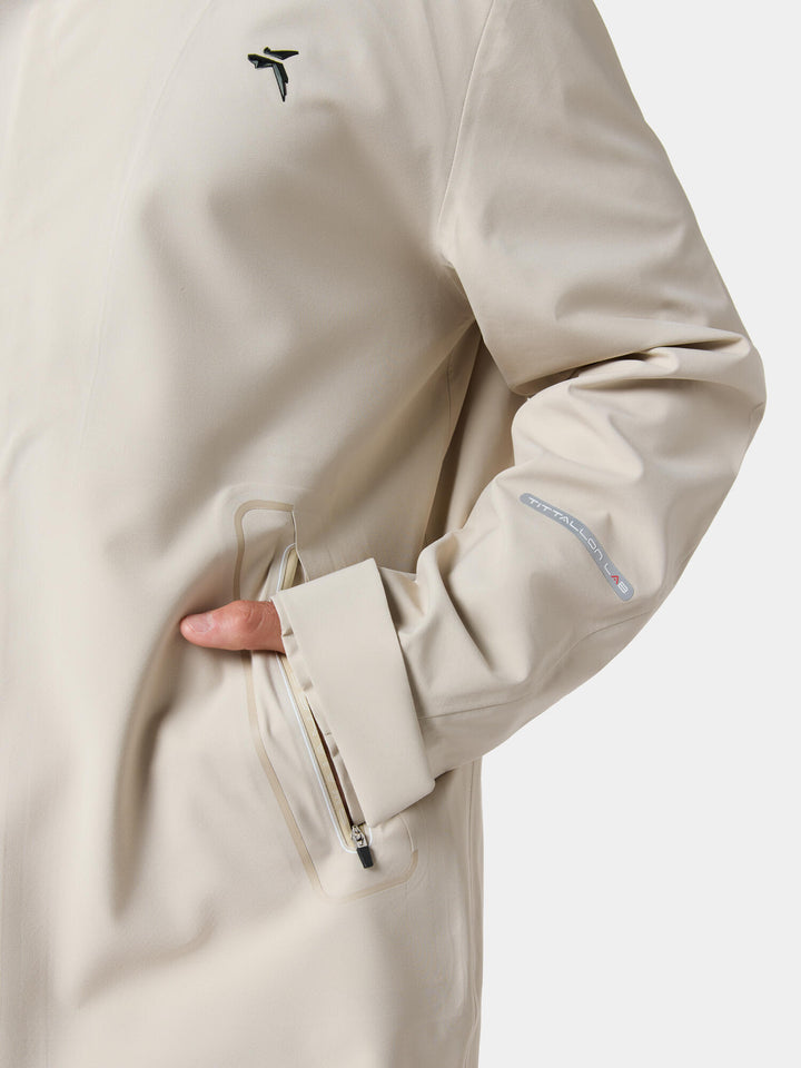 A hand in the zip hand pocket of the Urban Survival Recycled Casual Long Windbreaker Jacket in Sandstone Beige
