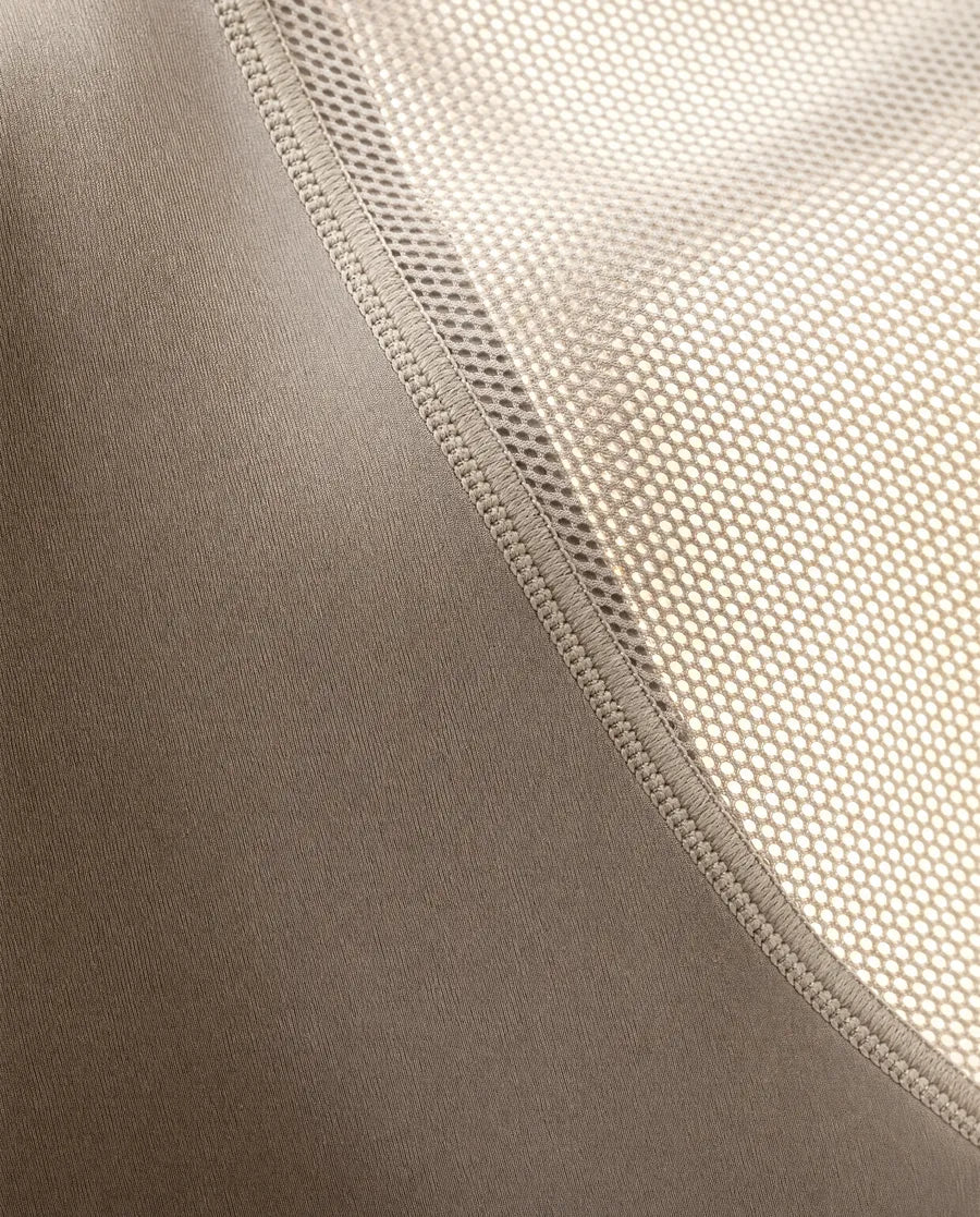 Macro of a dense compression fabric meeting a fine athletic mesh panel at a flatlock seam