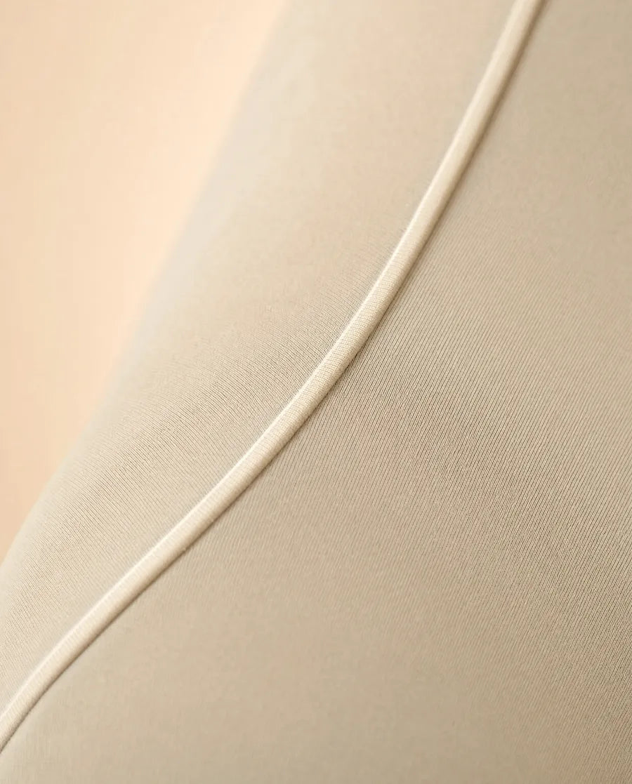 Macro of a heat-pressed bonded seam curving across a smooth cream compression fabric