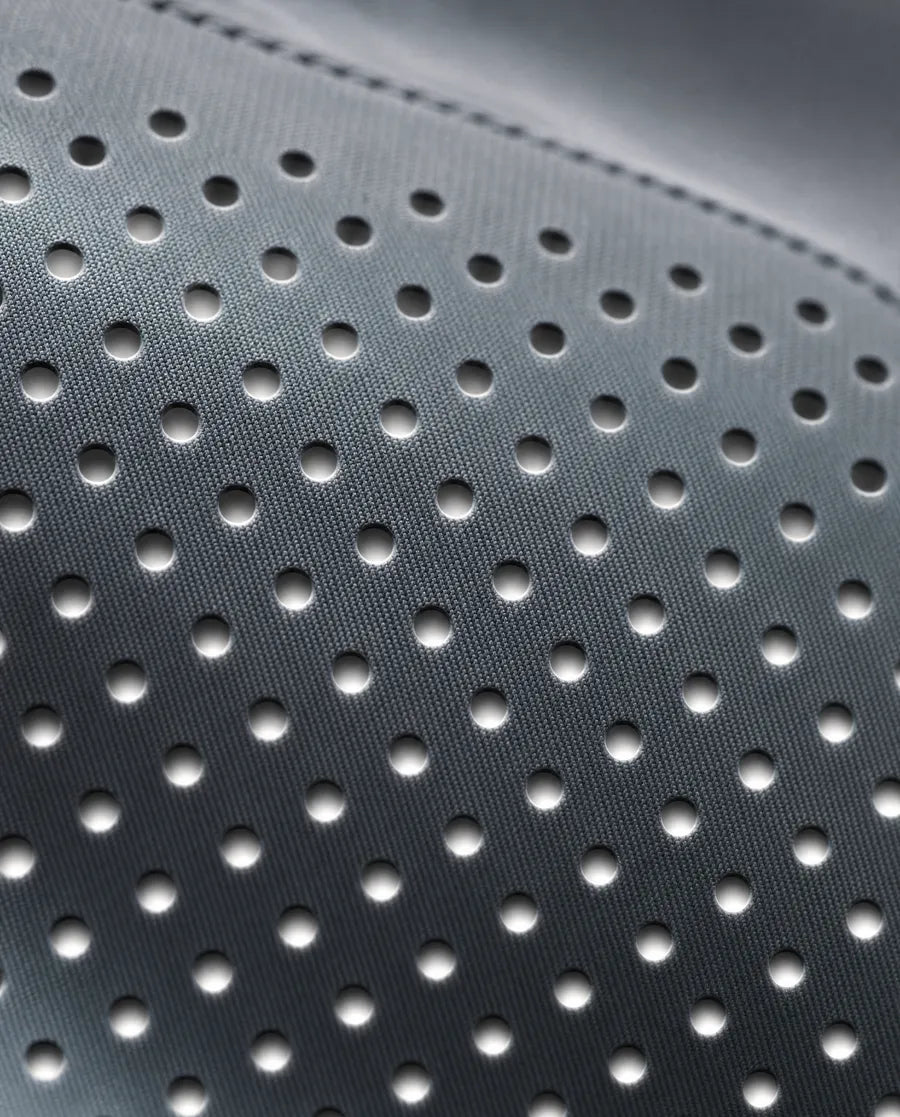 Macro of a precise grid of laser-cut ventilation perforations in slate nylon, backlit