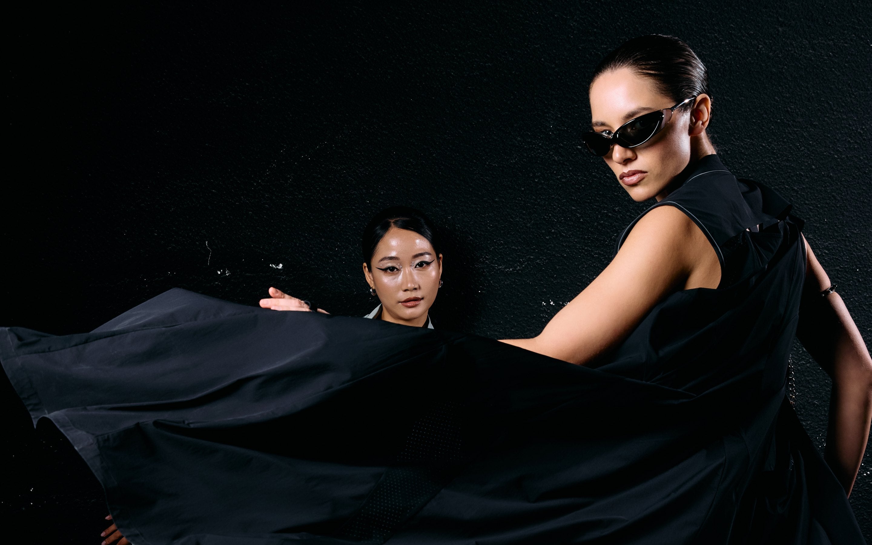 Two women in Fenggy black, a long black layer swung in motion