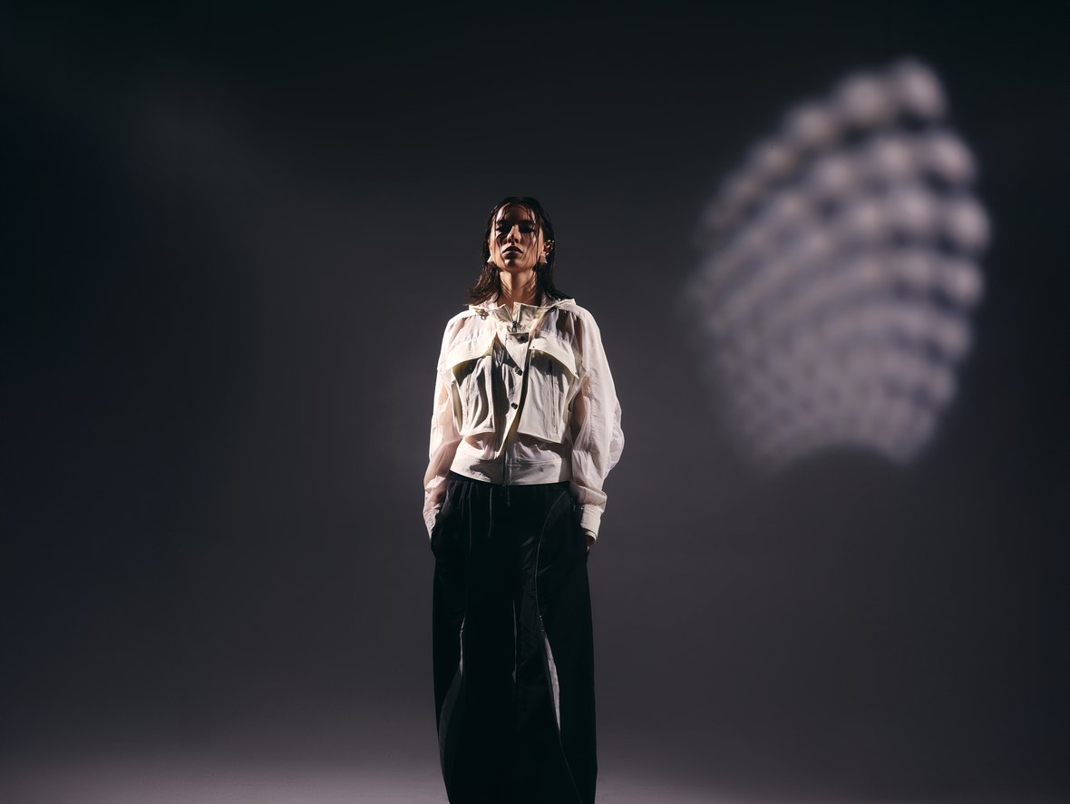 Fenggy: a woman in a cream utility windbreaker and wide black pants