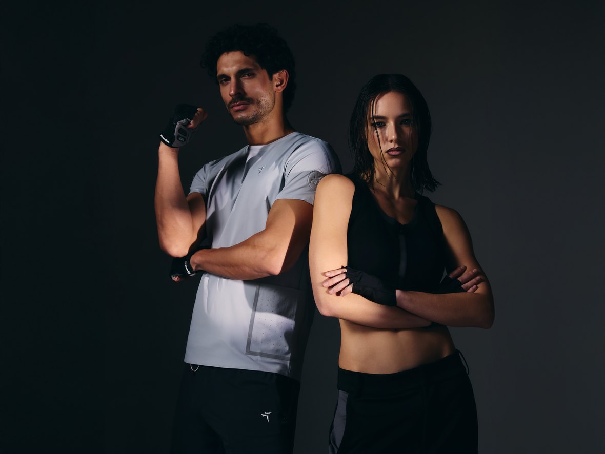 A man and a woman in NeoSpherium pieces under studio light: he wears the Tittallon Active Life Knitted Quick-Dry Relaxed Sport T-Shirt in Frost Gray, she wears the Fenggy SculptFit Zip Bra