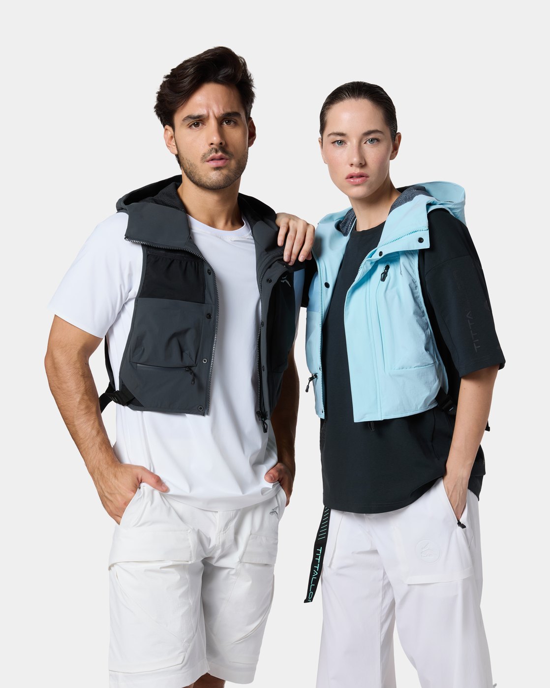 A man and a woman in the Tittallon Unisex Urban Explorer Water-Repellent Vest, his in Obsidian Gray, hers in Glacier Blue